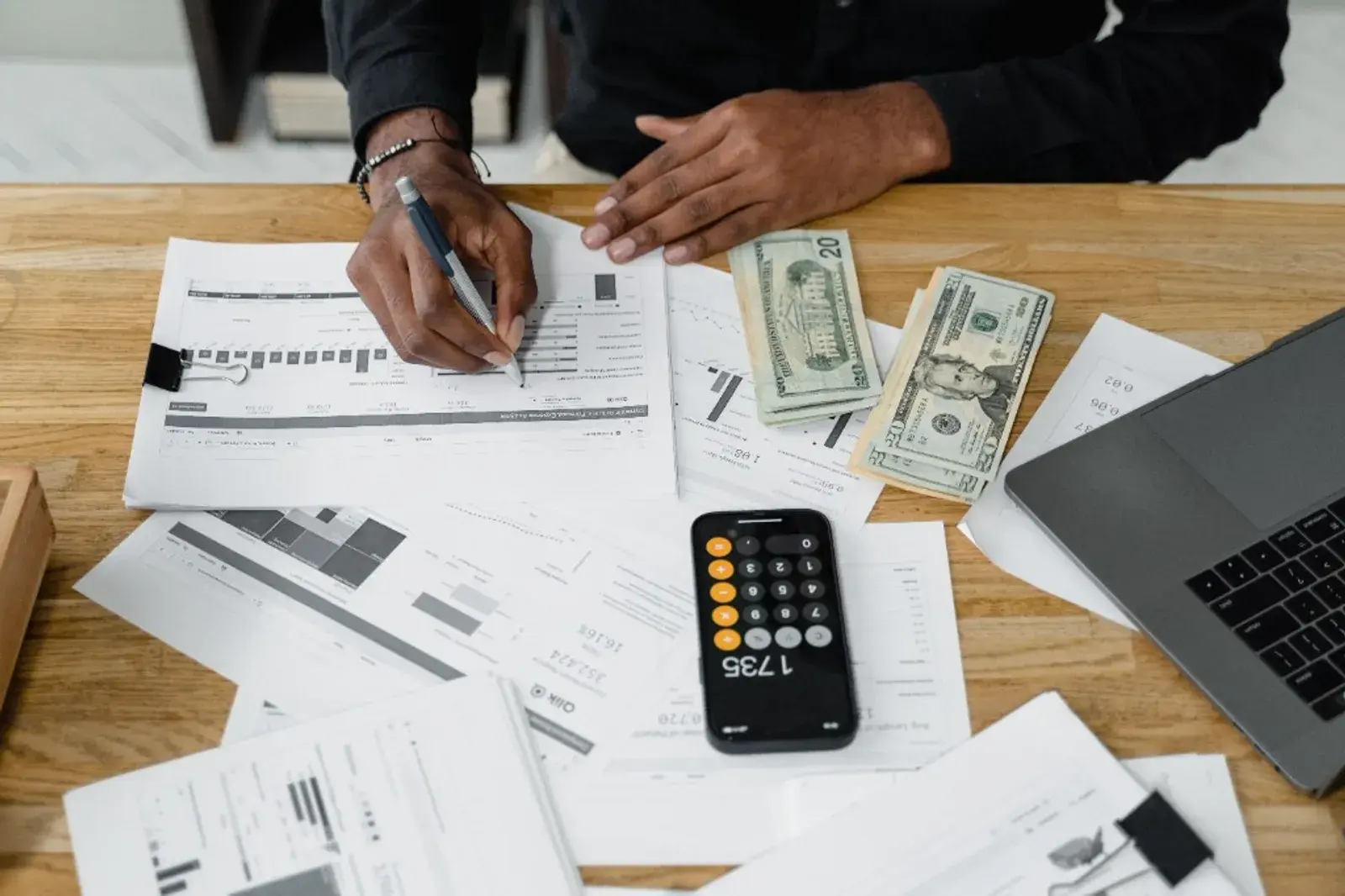 Forensic accountant reviewing financial documents, charts and calculations at a desk